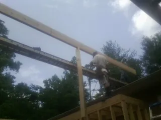 Carpenter setting a ridge beam over a new addition frame — Ice Dam Removal by Roofing Brothers in Tahuya
