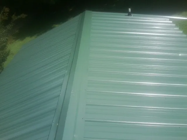 New green metal panels meeting at the ridge of a roof — Flat Roof Repair work by our crew in Tahuya