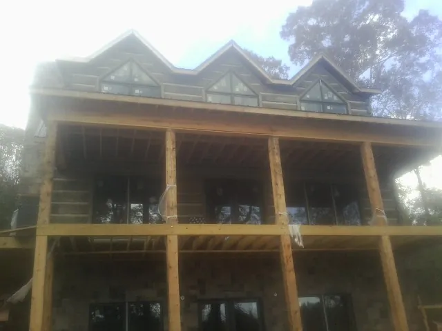 Dormers and porch framing on a large log home under construction — Roof Coating work by our crew in Tahuya