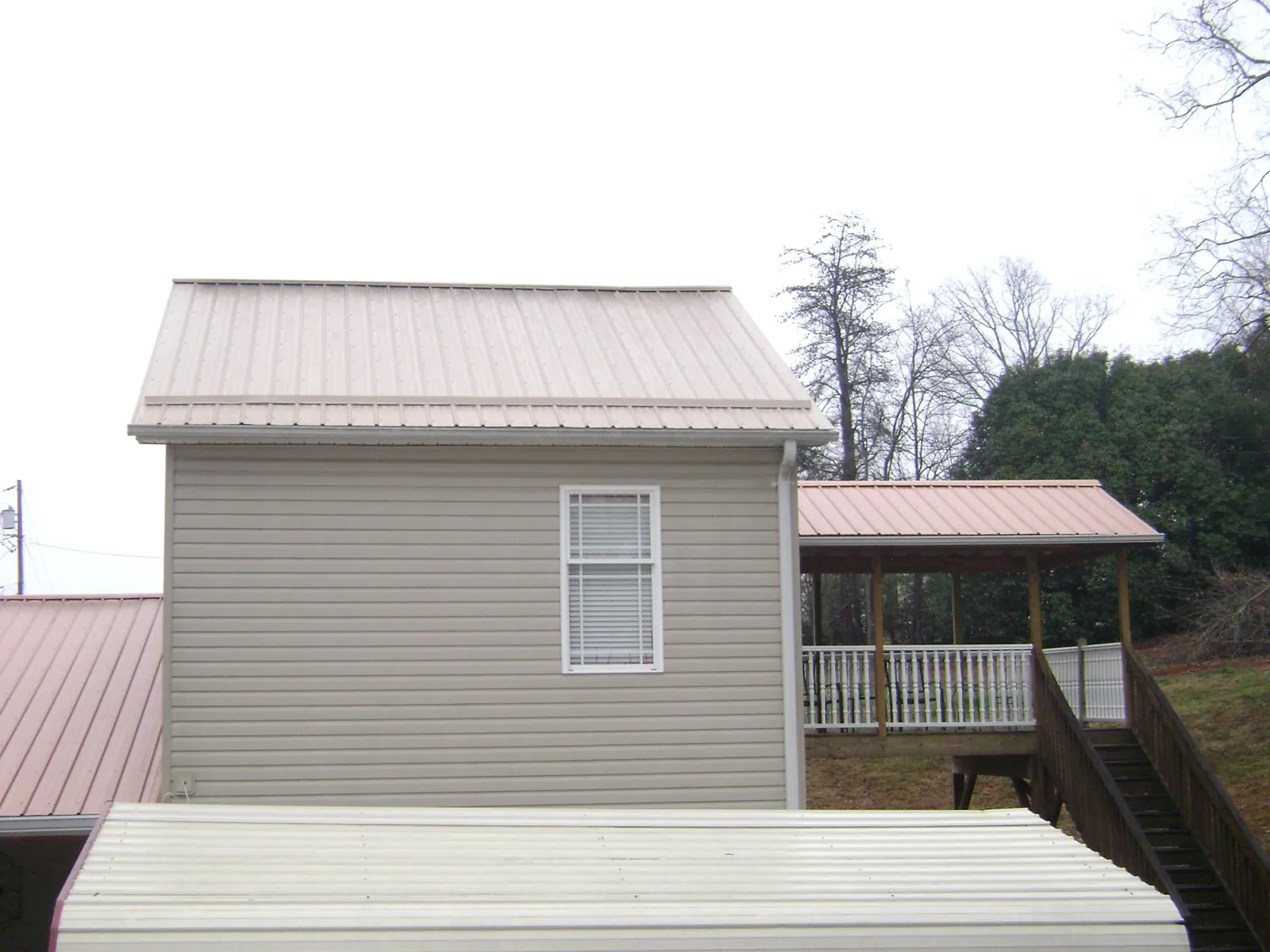 Tan metal roofs on a two story addition and attached porch, from a Roof Replacement job in Tahuya