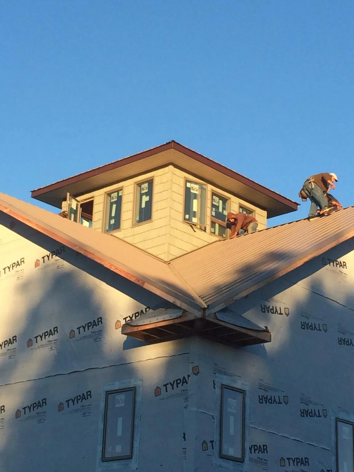 Roofers working around a rooftop cupola on a new metal roof at sunset — Roof Waterproofing in Tahuya by Roofing Brothers